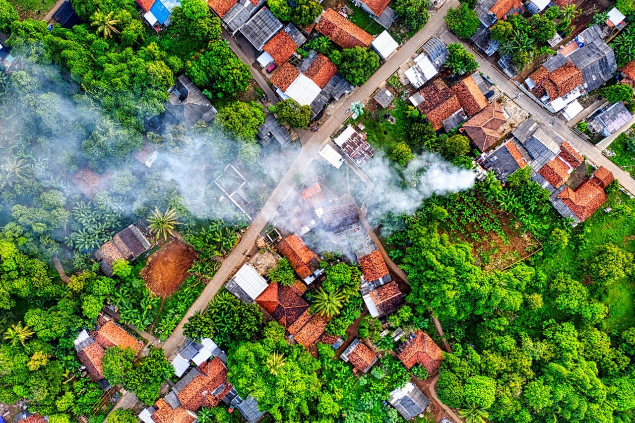 Drone view captures green village landscape with smoke in Banten, Indonesia.
